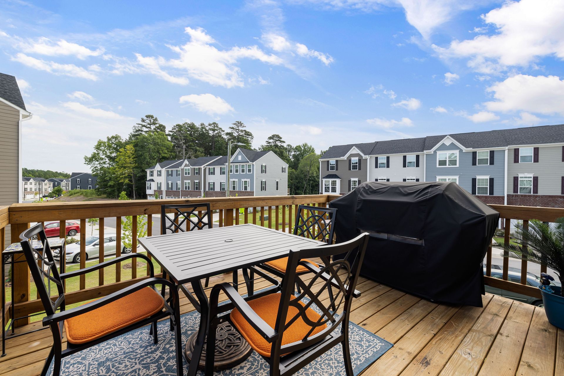 Charming wooden deck with furniture, grill, and suburban view.