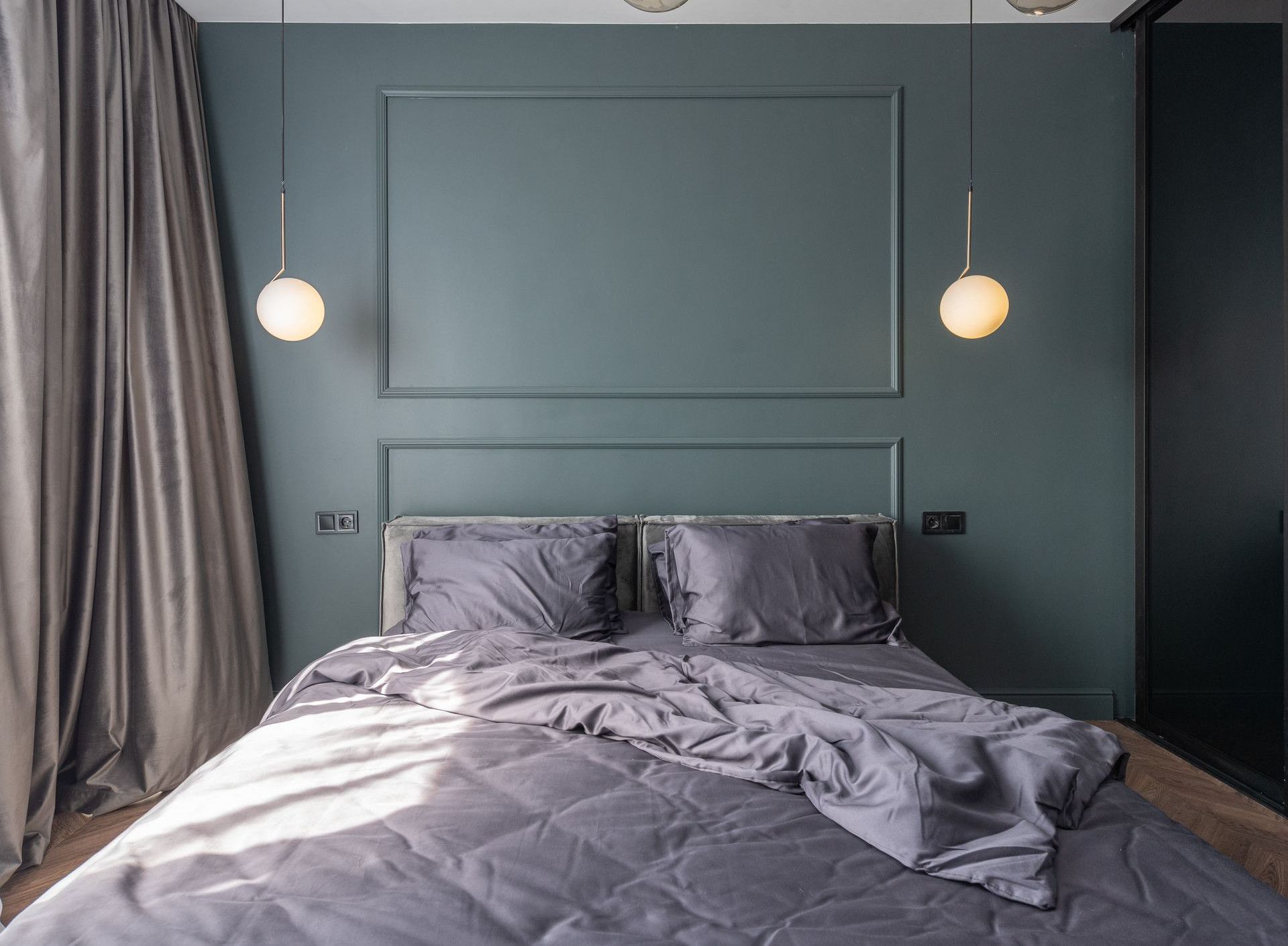 Interior design of modern bedroom with unmade bed under luminous lamps at sunlight